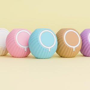 May include: Five spherical devices in pastel shades, each with a ridged exterior. Each has a circular centre in a contrasting colour. Colours include cream, pink, blue, tan, and purple. Measurements are in centimetres.