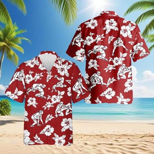 Könnte beinhalten: Rotes Hawaiihemd mit weißen Wrestling-Figuren und Hibiskusblüten. Das kurzärmelige Hemd hat eine Knopfleiste und eine lockere Passform. Das Design wiederholt sich auf der Vorder- und Rückseite des Hemdes, ideal für Freizeitkleidung.