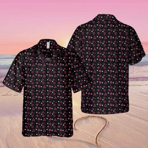 May include: Two black short-sleeved shirts with a repeating pattern of white and pink geometric shapes. The shirts are displayed on a beach with a pink and orange sunset in the background. The shirts have a button-down collar.