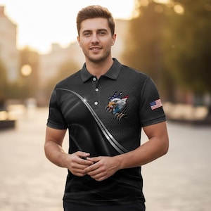 May include: Black polo shirt featuring an American flag eagle design. The shirt has a textured pattern and a silver stripe design. An American flag patch is on the sleeve.