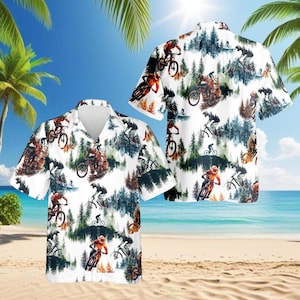 May include: White short-sleeved button-down shirt featuring a mountain biking design. The shirt showcases a repeating pattern of mountain bikers riding through a forest, with a blue sky and beach in the background.