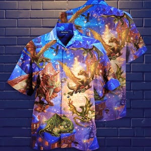 May include: Blue button-up shirt with a fantasy dragon print. The shirt features a vibrant design of dragons, buildings, and a starry sky. The word "DRAGON" is printed on the collar. The shirt is short-sleeved.