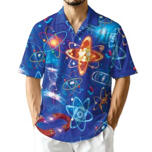 May include: A blue short-sleeved shirt with a button-down design, adorned with a repeating pattern of atomic structures in orange, yellow, and blue. The design includes atoms, magnets, and other scientific elements. The shirt has a classic collar and a relaxed fit.