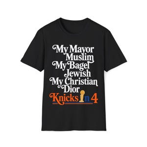 Può includere: Una t-shirt nera a maniche corte con testo bianco che recita My Mayor Muslim My Bagel Jewish My Christian Dior. Sotto, il testo Knicks in 4 appare in arancione e blu con una piccola icona di un trofeo di basket dorato tra le parole.
