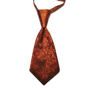 May include: A burnt orange tie with a floral pattern. The tie is made of a shiny fabric and has a classic shape. The tie is a solid color with a darker floral design.