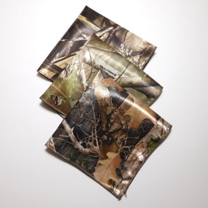 May include: Three camouflage fabric squares with the Realtree logo on one of the squares.