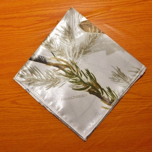 May include: White satin fabric with a camouflage pattern featuring pine branches and the text "REALTREE".