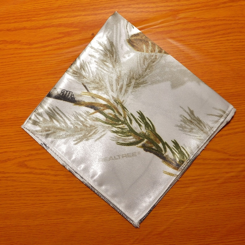 May include: White satin fabric with a camouflage pattern featuring pine branches and the text "REALTREE".