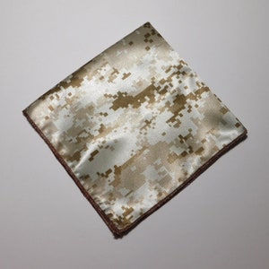 May include: A white and brown camouflage patterned pocket square with a brown border.