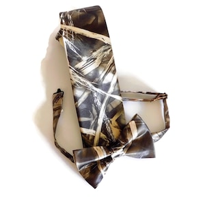 May include: A brown and tan camouflage patterned bow tie and matching necktie. The bow tie is pre-tied and the necktie is made of satin.