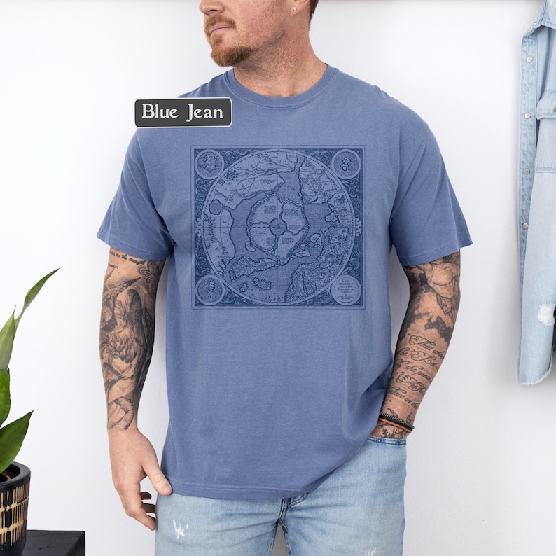 May include: A blue jean t-shirt with a vintage map print on the front. The map is in black and white and shows the world. The shirt is a relaxed fit and has a crew neck.