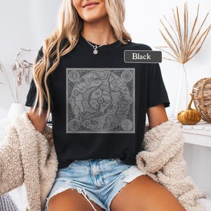 May include: A black t-shirt with a vintage map graphic printed on the front. The map is in shades of gray and features a compass rose and other details. The text "Black" is visible on the shirt.