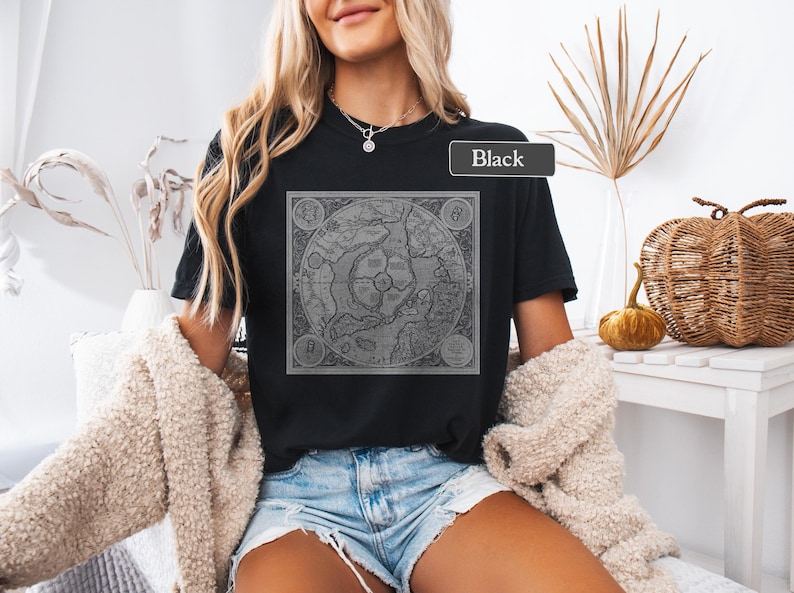 May include: A black t-shirt with a vintage map graphic printed on the front. The map is in shades of gray and features a compass rose and other details. The text "Black" is visible on the shirt.