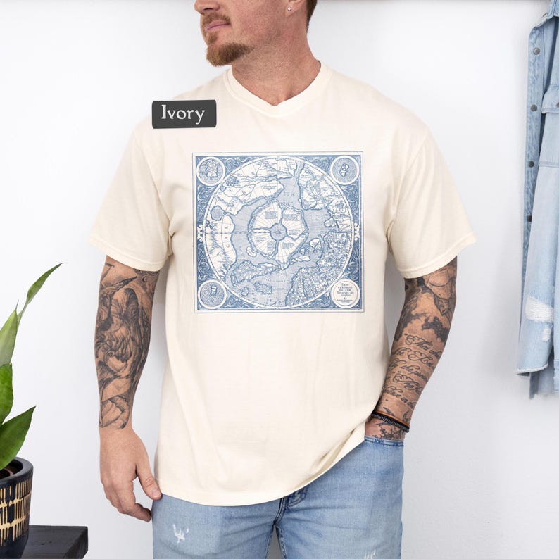May include: A cream colored t-shirt with a vintage map print in blue. The map is centered on the shirt and is surrounded by a square border. The text "Ivory" is visible in the top left corner of the image.