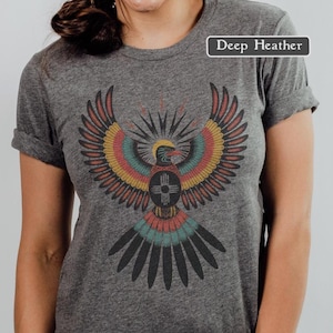 May include: Deep heather gray t-shirt featuring a colorful eagle design with a sunburst and geometric elements. The eagle has red, yellow, teal, and black details. The text "Deep Heather" is in a white rectangle.