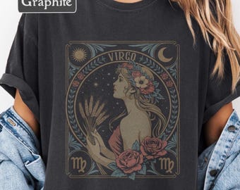 May include: Graphite-colored t-shirt featuring a Virgo zodiac design. The graphic includes a woman's profile, wheat, roses, and the word "Virgo" in a decorative frame. The design incorporates shades of red, blue, and gold.