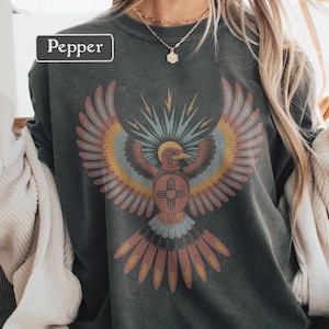 May include: Dark gray sweatshirt with a colorful graphic of a bird with outstretched wings. The bird design features shades of red, yellow, blue, and orange. The word "Pepper" is printed in a white rectangle at the top left.