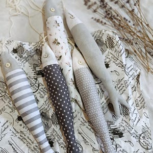Peut inclure: Plusieurs jouets en forme de poisson en tissu faits à la main, aux motifs et couleurs variés. Les poissons présentent des motifs à rayures, étoiles, floraux et géométriques. Chaque poisson a un bouton pour les yeux et une ficelle pour suspendre.