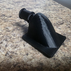 May include: A black 3D-printed object with a flared base and a cylindrical nozzle. The object has a smooth, matte finish and appears to be a custom-designed component. The design is modern and functional.