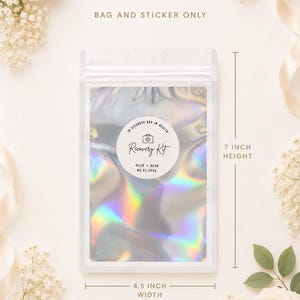 May include: A holographic, iridescent pouch with a white zipper seal, measuring 7 inches in height and 4.5 inches in width. A circular white sticker on the front features a camera icon, the text In Sickness and in Health, Recovery Kit, Allie + Dean, and 06.01.2026.