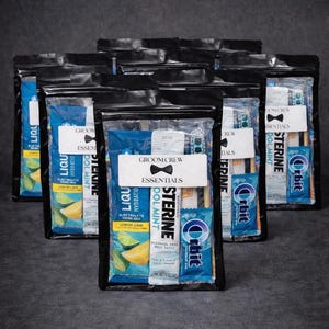 May include: Several black zippered pouches filled with grooming essentials. Each pouch contains items like mouthwash, gum, and electrolyte drink mix. The pouches have a white label that reads "GROOM CREW ESSENTIALS" with a bow tie graphic.
