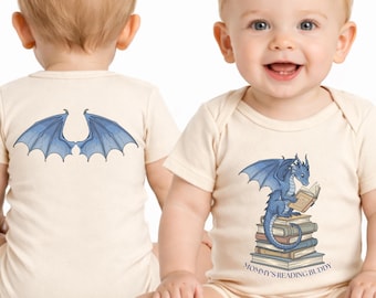 Puede incluir: Dos bodies de bebé beige. Uno presenta alas de dragón azules en la espalda. El otro tiene un dragón azul leyendo sobre libros, con el texto "Mommy's Reading Buddy".