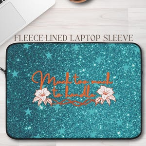 May include: A teal glitter laptop sleeve with a black zipper and the text "Much too much to handle" in orange script. The design includes teal stars and white and orange floral accents. The words "Fleece-lined laptop sleeve" are at the top.