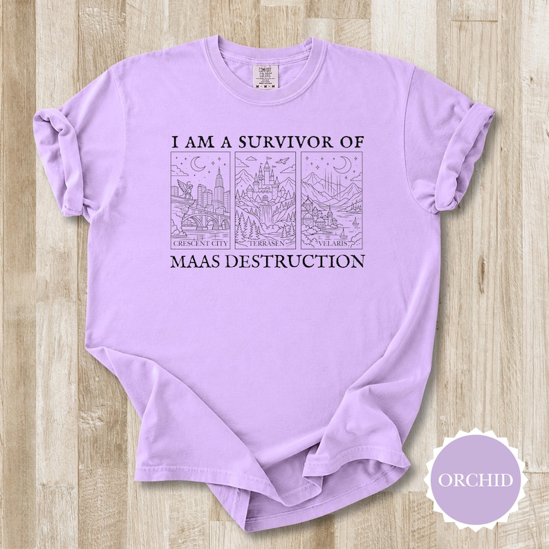 K&ouml;nnte beinhalten: Orchideenfarbenes T-Shirt mit dem Text "I AM A SURVIVOR OF MAAS DESTRUCTION". Das Design zeigt drei illustrierte Tafeln: Crescent City, Terrasen und Velaris. Das Shirt besteht aus einem weichen, bequemen Material.
