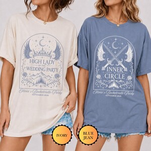 Puede incluir: Dos camisetas de manga corta y cuello redondo en color marfil y azul. La camiseta marfil presenta una corona, alas y el texto High Lady of the Wedding Party. La azul muestra espadas cruzadas, alas y el texto Inner Circle. Ambas incluyen el texto Olivia's Bachelorette Party September 2026.