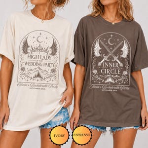 Puede incluir: Dos camisetas de manga corta y cuello redondo en color marfil y espresso. La camiseta marfil presenta una corona, alas y el texto High Lady of the Wedding Party, Olivia's Bachelorette Party, September 2026. La camiseta espresso muestra espadas cruzadas, alas y el texto Inner Circle, Olivia's Bachelorette Party, September 2026.