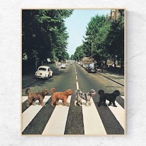 May include: A framed print featuring four dogs crossing a street on a crosswalk, mimicking the iconic Abbey Road album cover. The dogs are various colors, including brown, orange, and black. The background shows a street with cars and trees.