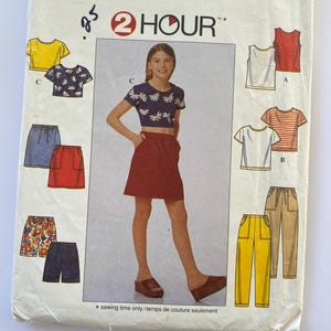 May include: A sewing pattern for a girl's skirt and tops. The pattern includes a red skirt, a yellow striped top, a white top with red stripes, a white top with a floral print, a blue skirt, and a pair of yellow pants. The pattern is labeled "2 Hour" and includes instructions for sewing the garments.