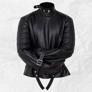 May include: Black leather straight jacket with a high collar and quilted shoulder details. The jacket features a buckle closure and straps to secure the arms. The garment is designed to restrict movement.