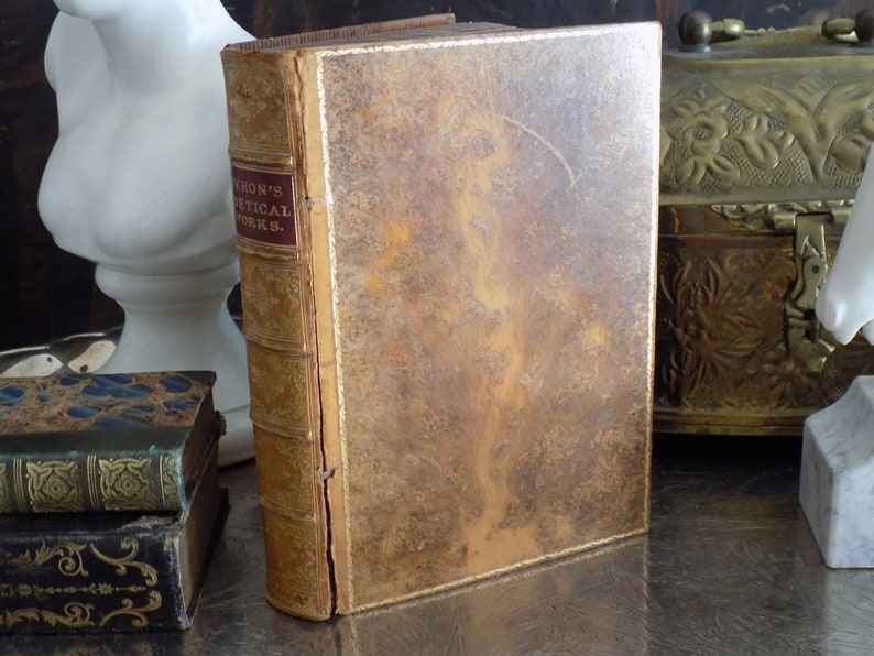 May include: A vintage leather-bound book with gold accents and the title "Byron's Poetical Works." on the spine.