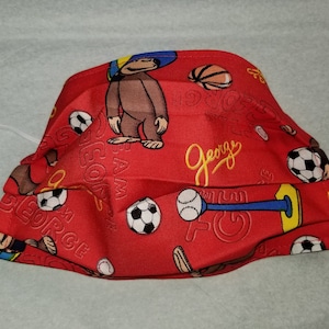 May include: Red fabric face mask with a repeating pattern of a cartoon monkey, basketballs, soccer balls, and the text "George".
