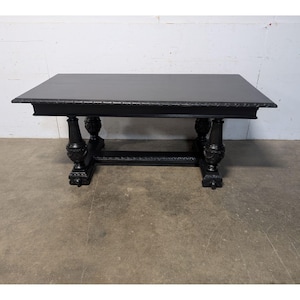May include: A black rectangular table with ornate carved legs and a decorative edge. The table is approximately 152 cm long and 76 cm wide, with a dark finish. The table is made of wood and is suitable for a dining room or living room.