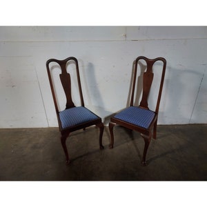 May include: Two wooden chairs with blue and white checkered upholstery. The chairs have a traditional design with cabriole legs and a carved back.