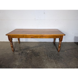 Puede incluir: Una mesa de comedor de madera rústica con una tapa rectangular y patas torneadas. La mesa está hecha de madera natural con un acabado marrón cálido.