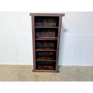 May include: A dark brown wooden bookshelf with five shelves. The bookshelf has a rectangular shape with decorative carvings along the sides and top. The shelves are evenly spaced, and the wood has a rich, warm tone.
