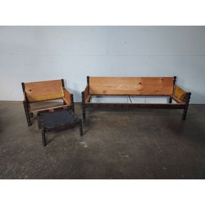 May include: A three-piece furniture set featuring a sofa, armchair, and small table. The wooden frames are dark brown with turned legs and arm supports. The sofa and armchair have wooden backs, while the table has a black surface.