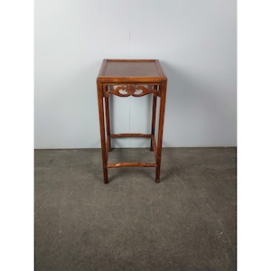 May include: A small, square, wooden table with intricate carvings on the top and sides. The table has a dark brown finish and stands on four legs.
