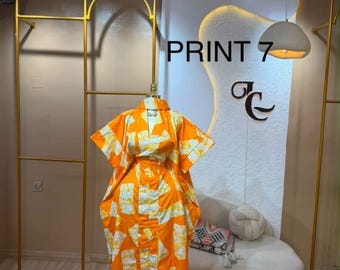 Könnte beinhalten: Ein bodenlanges Kaftan-Kleid mit einem leuchtend orange-weißen, abstrakten geometrischen Muster. Das Kleidungsstück hat kurze, weite Ärmel, einen hohen Ausschnitt und eine lockere, fließende Silhouette, die von den Schultern bis zum Boden reicht.