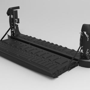 Puede incluir: Un conjunto de portón trasero de camión negro, con una superficie texturizada y herrajes de soporte. El portón trasero está abierto, revelando su estructura interna. La imagen es una representación en escala de grises, destacando el diseño del producto.