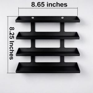 May include: A black, wall-mounted shelf unit with four tiers. The unit is 8.65 inches wide and 8.25 inches tall. The shelves are rectangular and have a small lip to prevent items from falling off. Two small, decorative accents are visible.