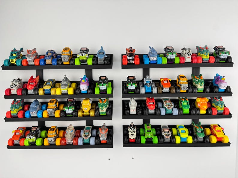 May include: Collection of colorful toy monster trucks displayed on black wall-mounted shelves. Each truck features unique designs and vibrant colors, including red, blue, green, and yellow. The collection is arranged on three shelves.