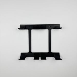May include: Black metal wall-mounted organizer with a rectangular frame and multiple hooks. The organizer has a symmetrical design with two vertical supports and several horizontal bars for storage and display.