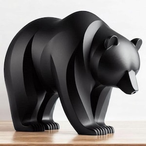 Puede incluir: Escultura de oso negro mate con un diseño geométrico estilizado. El oso está de pie, con garras visibles y una cara detallada. La escultura está colocada sobre una superficie de madera, con un fondo blanco liso.