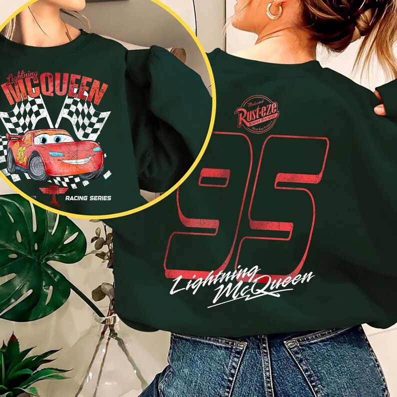 May include: Dark green sweatshirt featuring Lightning McQueen from the Cars movie. The front displays McQueen with a checkered flag and the text "Racing Series." The back shows the number "95" and the text "Lightning McQueen."