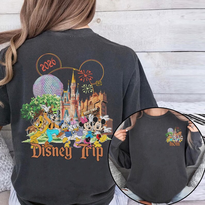 May include: Dark gray sweatshirt featuring a colorful Disney Trip design with Mickey Mouse, Minnie Mouse, and other characters. The design includes a castle, fireworks, and the year 2026. A smaller version of the design is on the sleeve.