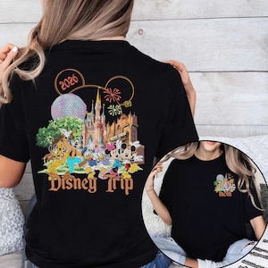 May include: Black t-shirt featuring a colorful Disney Trip design with Mickey Mouse, Minnie Mouse, and other characters. The design includes the text "2026" and a smaller design on the front that says "mom".